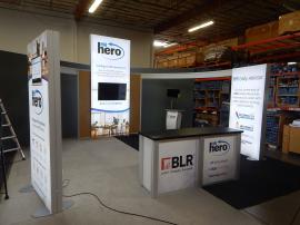 RENTAL: Modified RE-9096 Island with (3) Double-Sided Lightboxes, Curved Bridged Extrusion Headers, RE-1207 Large Rectangular Counter, (2) RE-1213 Counter Kiosks, Silicone Edge Fabric Graphics for Lightboxes, and Direct Print Sintra Graphics for Counters