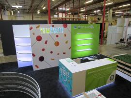 Custom Inline Exhibit with Gravitee and Custom Construction. Design Includes Backlit Logo, Shelves, LED Edge Lighting, Reception Counters with Storage, Closet, and Fabric and Direct Print Graphics