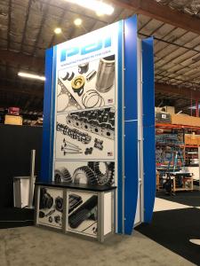 Modified RE-9013 Island Design with 16 ft High Storage Tower with Locking Door, (2) RE-1223 Tapered Counter Kiosks, (2) RE-1207 Large Rectangular Counters, (6) LED Arm Lights, SEG Fabric Graphics, and Direct Print Sintra Graphics.